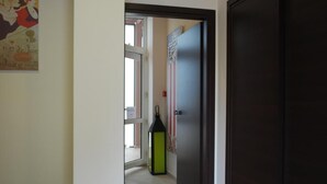 Un corridoio con una porta, una finestra e un punto luce a parete.