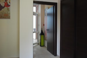 A hallway with a door, a window, and a wall-mounted light fixture.