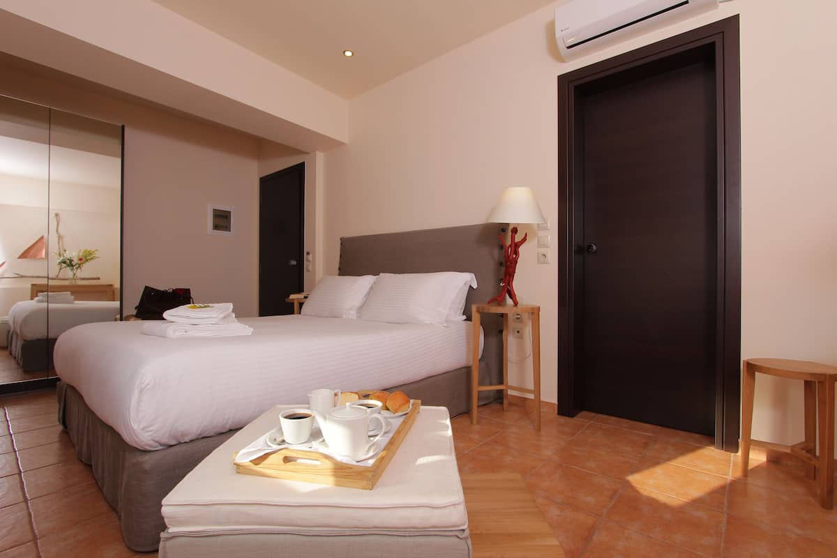 Una habitación de hotel con cama, mesita de noche y una bandeja con alimentos para el desayuno.