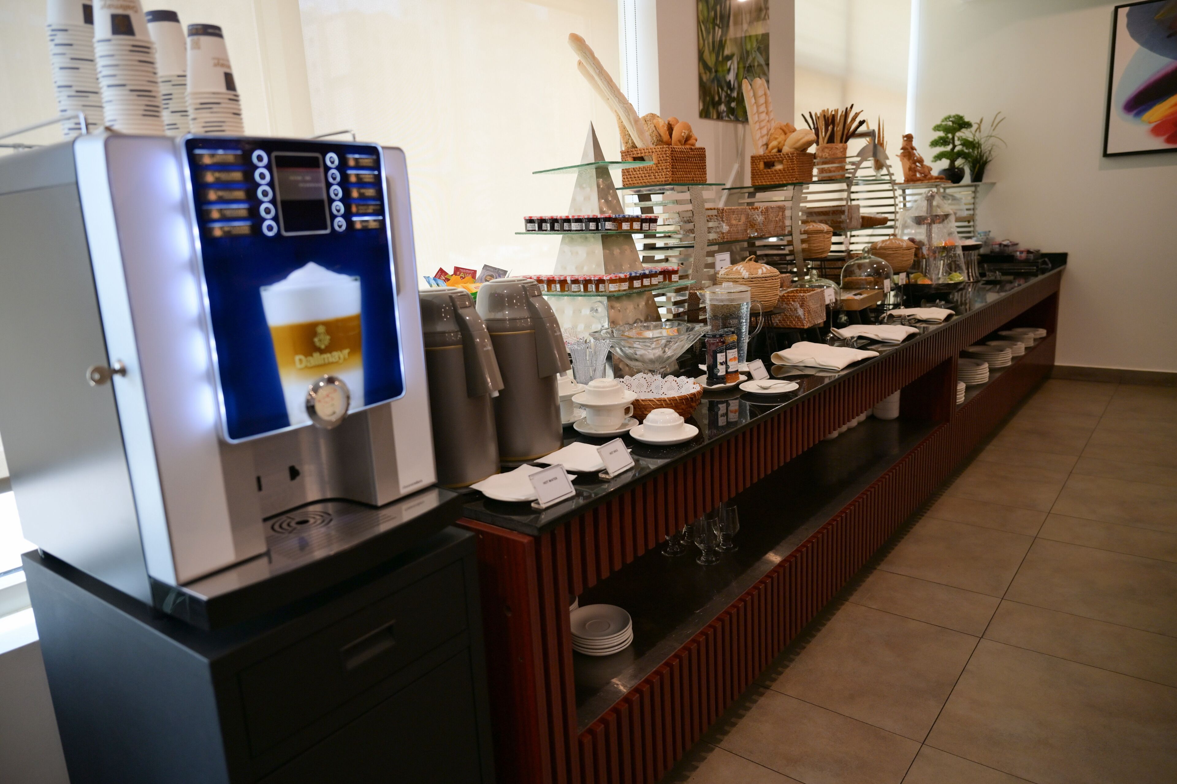 A buffet setup with a coffee machine, various food items, and glassware.