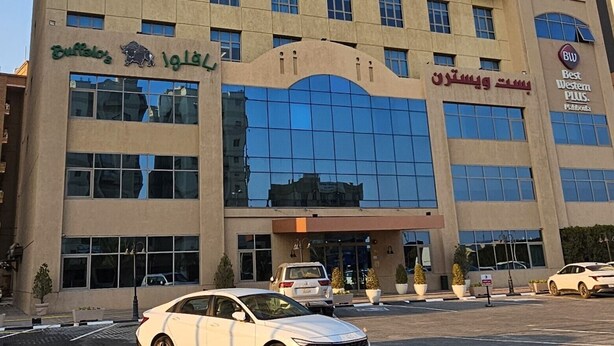 A tall hotel building with multiple floors, a glass entrance, and a sign indicating it is a Best Western Plus property.