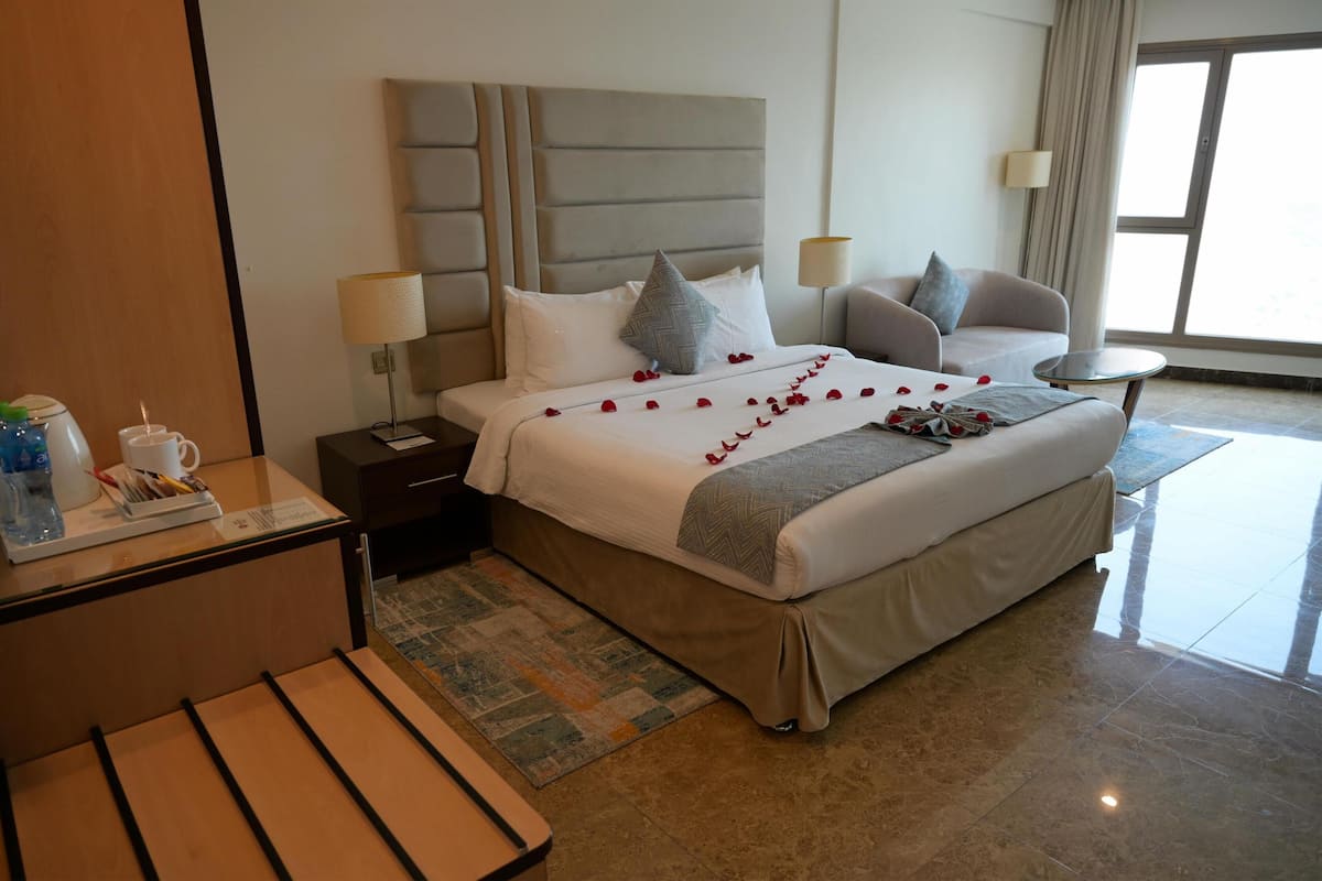 Quarto de hotel com cama, mesas de cabeceira, escrivaninha e uma cadeira.