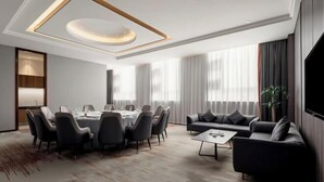 Una moderna camera d'hotel con zona pranzo, divano e televisione a schermo piatto.