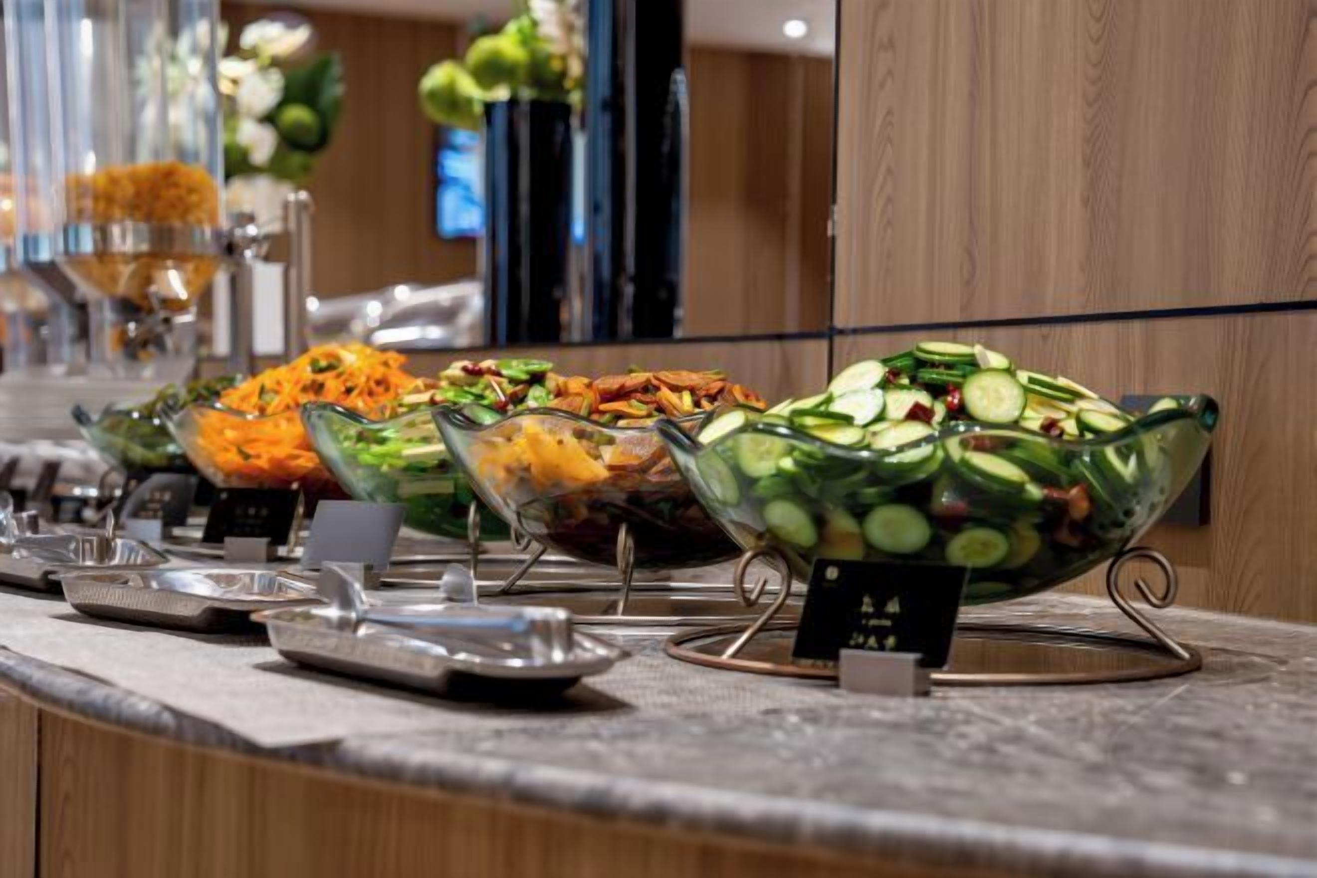 Een buffet met diverse gerechten in glazen schalen, gerangschikt op een toonbank.