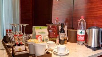 Disposição para o café da manhã em um quarto de hotel, com máquina de café, chaleira e diversos alimentos.