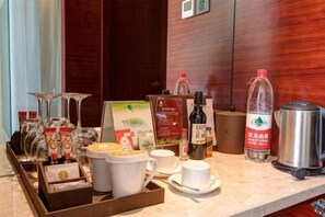 Preparación de desayuno en una habitación de hotel, con cafetera, hervidor de agua y diferentes alimentos.
