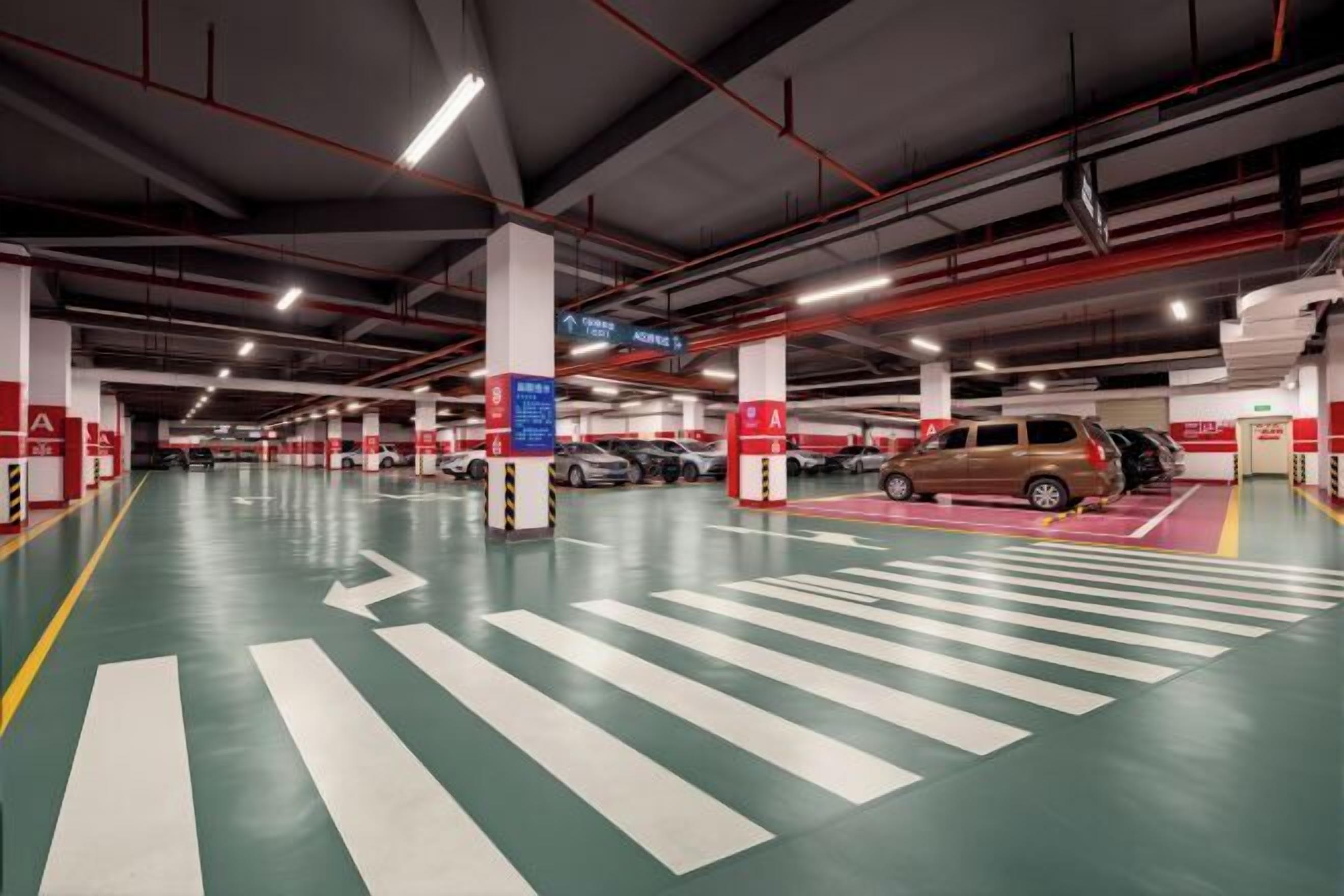 A multi-level parking garage with clear directional arrows on the floor, multiple parking spaces, and red safety signs.