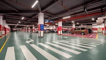A multi-level parking garage with clear directional arrows on the floor, multiple parking spaces, and red safety signs.