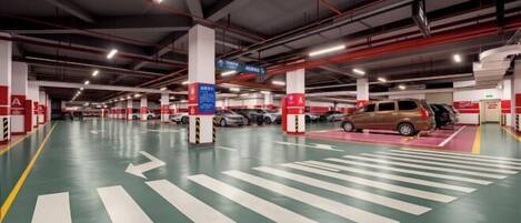 Un estacionamiento de varios niveles con flechas direccionales claras en el suelo, múltiples espacios de estacionamiento y señales de seguridad rojas.