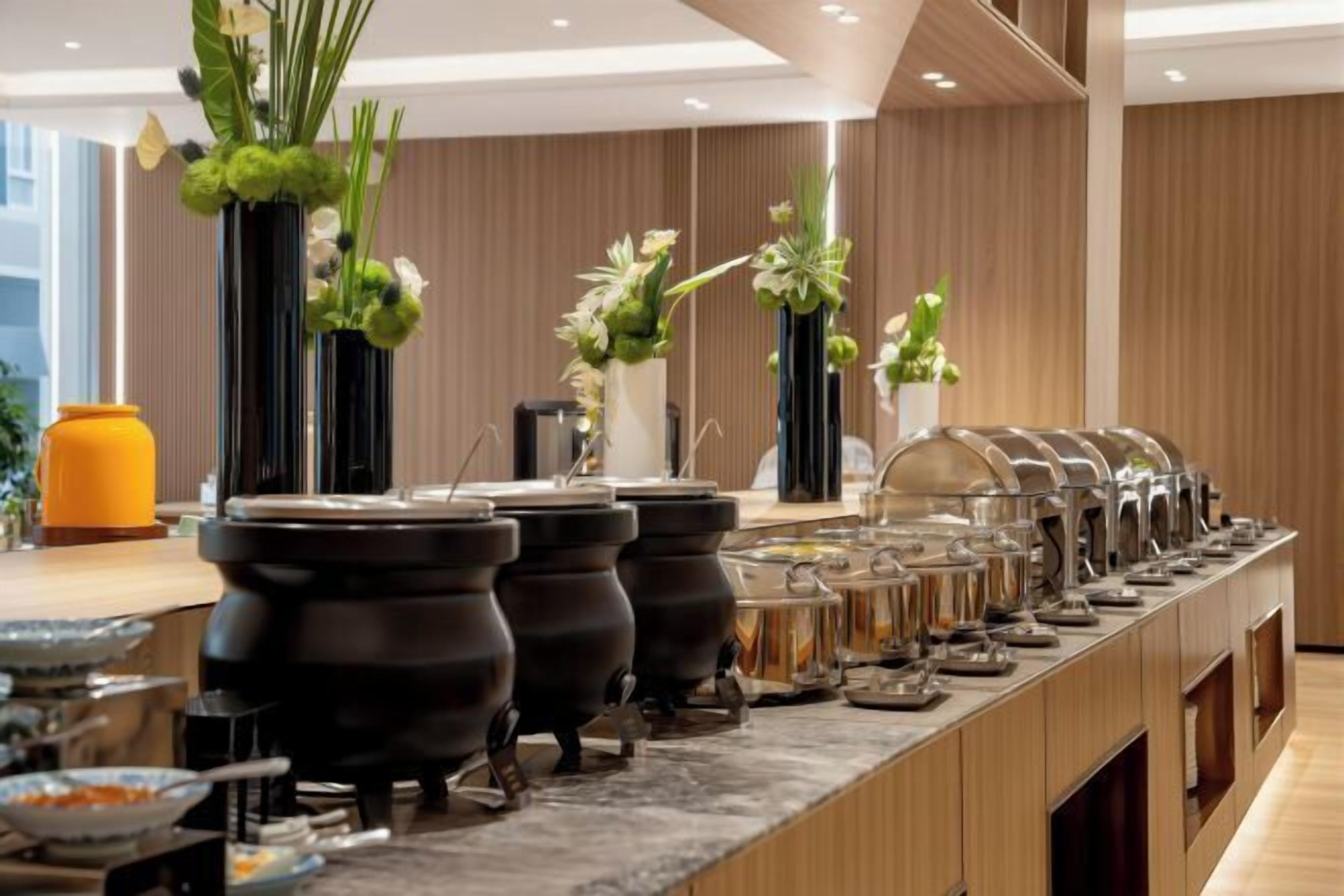 Disposição de buffet com várias estações de serviço e vasos decorativos.