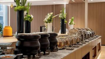 Disposição de buffet com várias estações de serviço e vasos decorativos.