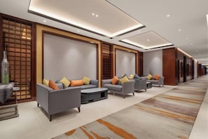 A hotel lobby with a seating area, a reception desk, and a decorative wall. - Intercity Hotel (Baoji)