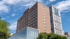 Un edificio a più piani con facciata in vetro e esterno marrone, circondato da alberi.
