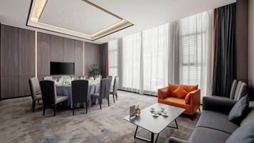 Una habitación de hotel moderna con comedor, sofá y televisor.