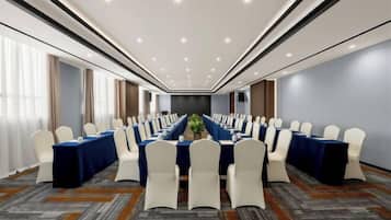 A conference room with a long table, white chairs, and a blue tablecloth.