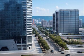 A modern urban street with high-rise buildings, a clear sky, and a well-maintained road with vehicles and trees. - Intercity Hotel (Baoji)