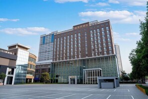 A modern hotel with a glass facade, a central entrance, and a parking lot. - Intercity Hotel (Baoji)