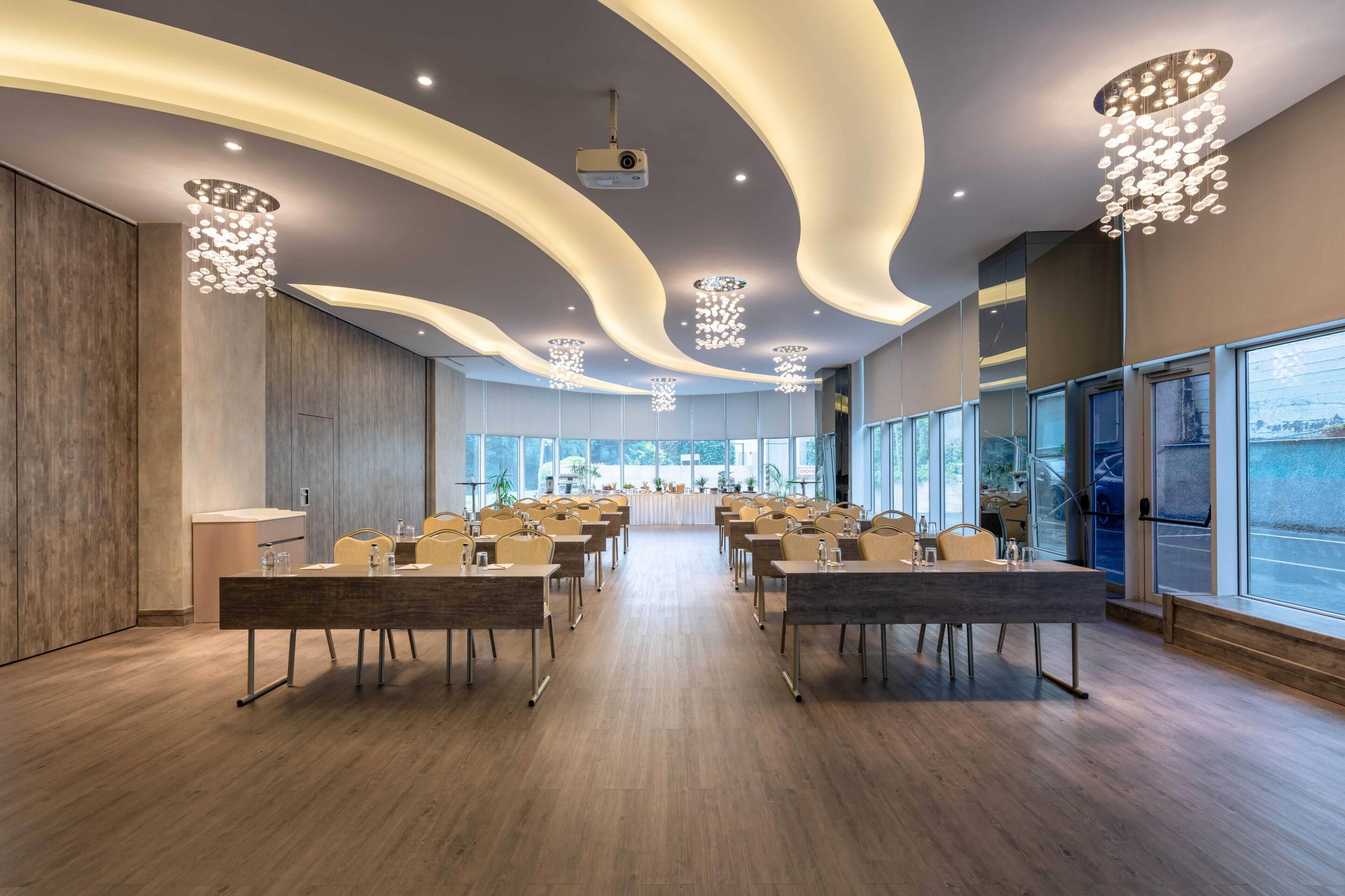 A modern conference room with curved ceiling lights, wooden floors, and large windows.