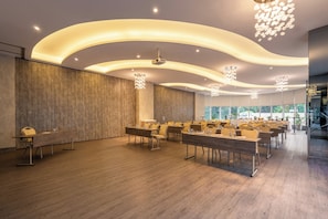 Ein Konferenzraum mit modernem Design, der durch gebogene Deckenleuchten, Holzwandverkleidungen und ein großes Fenster mit Blick ins Freie gekennzeichnet ist.