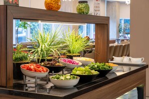 A buffet with various food items and a decorative plant arrangement. - Ramada Encore by Wyndham Istanbul Bayrampasa (Istanbul)