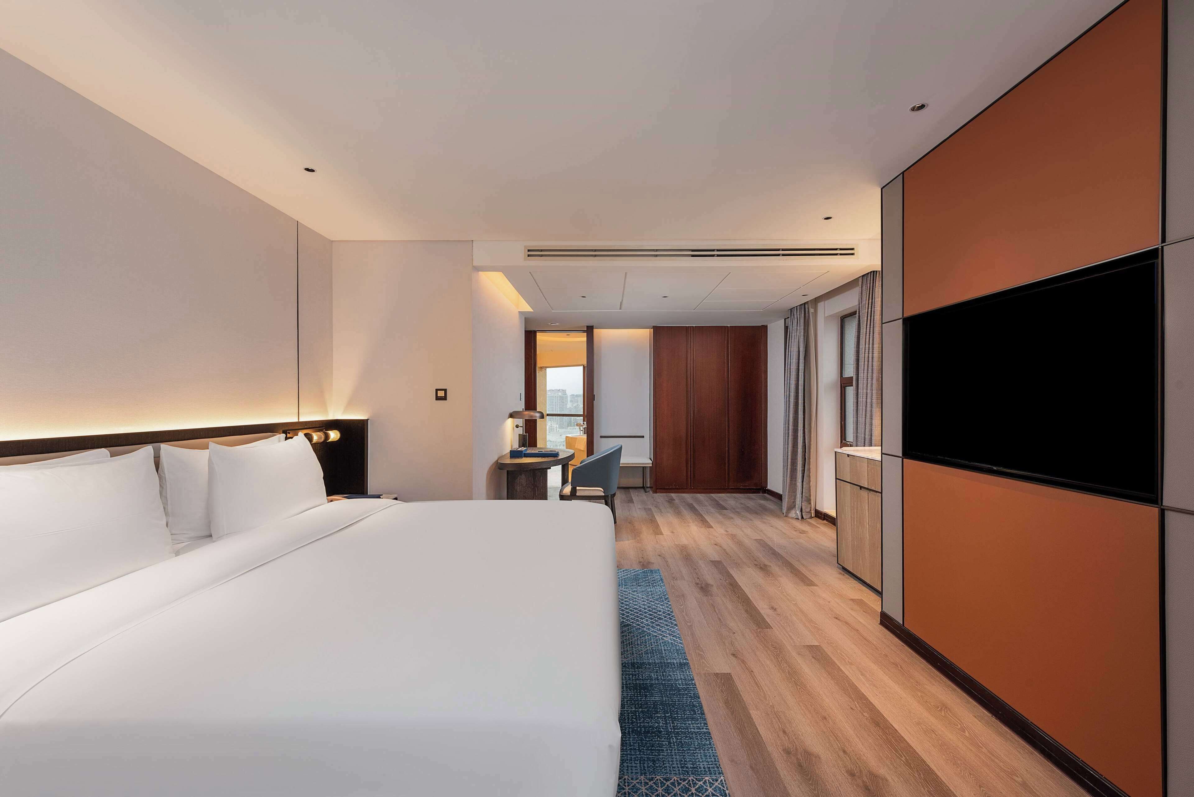 Une chambre d’hôtel moderne équipée d’un grand lit, d’un bureau avec une chaise, d’une télévision et d’une armoire.