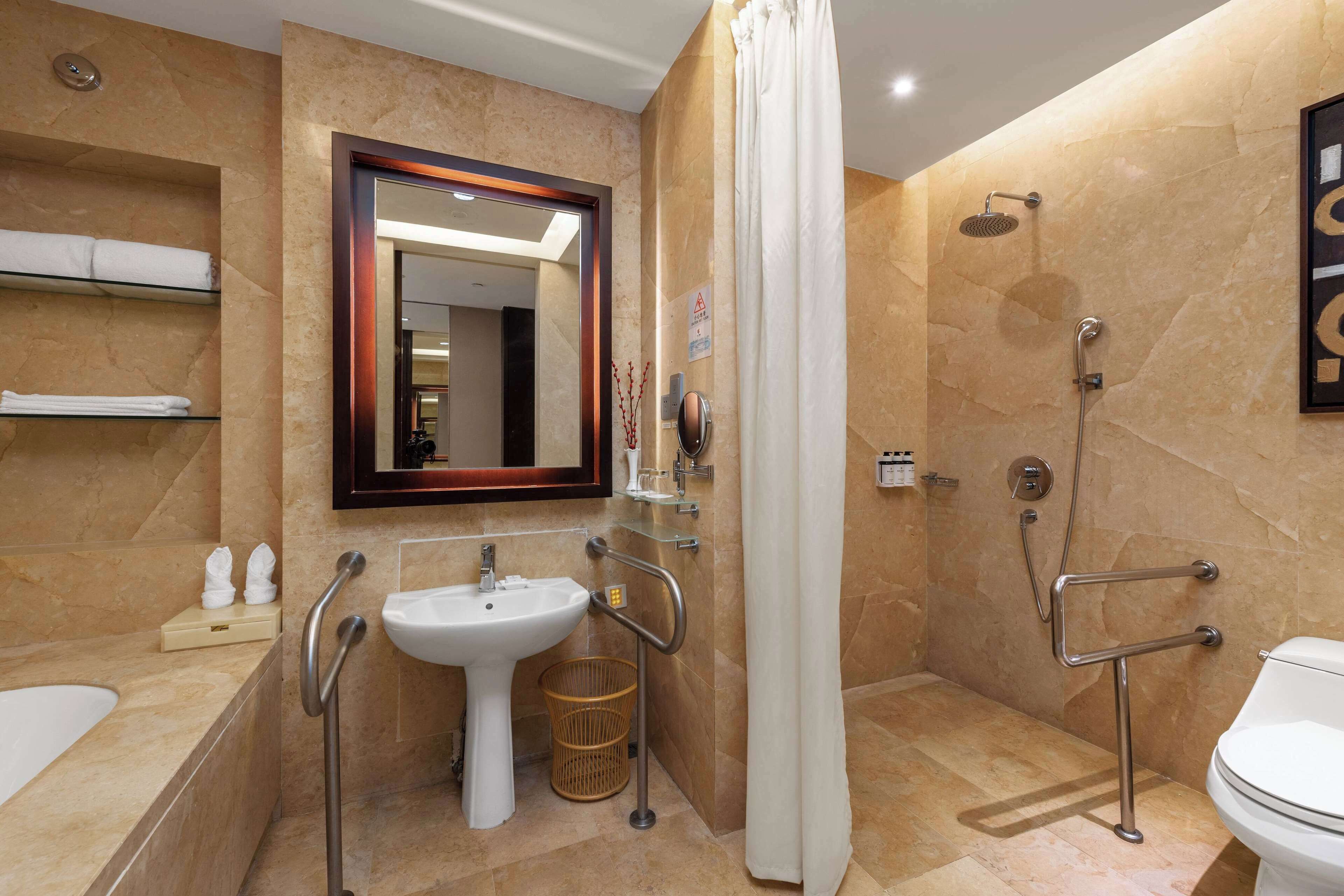 Un baño moderno con lavamanos, espejo, ducha e inodoro.