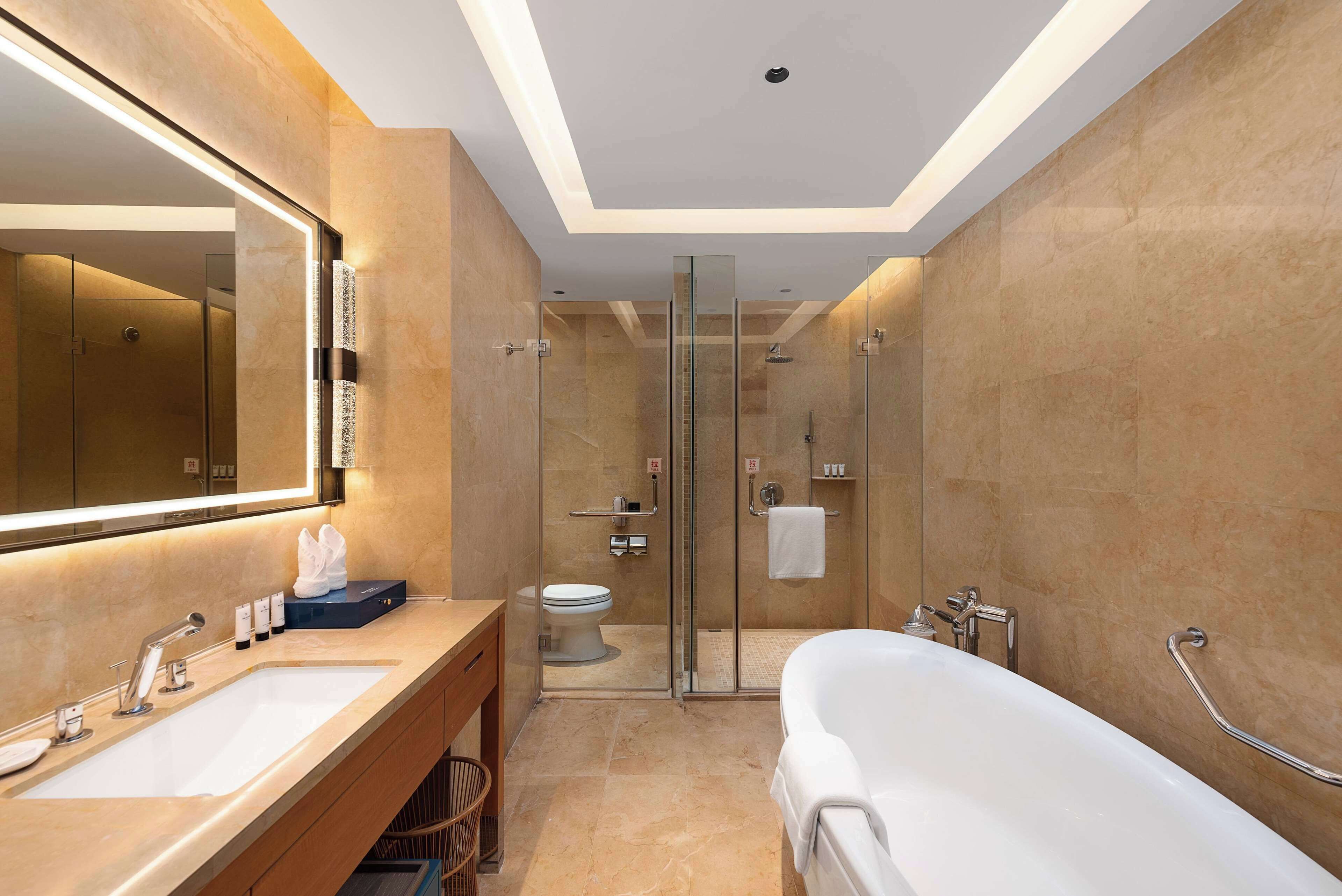 A modern bathroom with two sinks, a glass-enclosed shower, and a large bathtub.