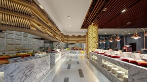 Un hall d’hôtel moderne avec des comptoirs en marbre, un espace salon central et un plafond décoratif en bois.