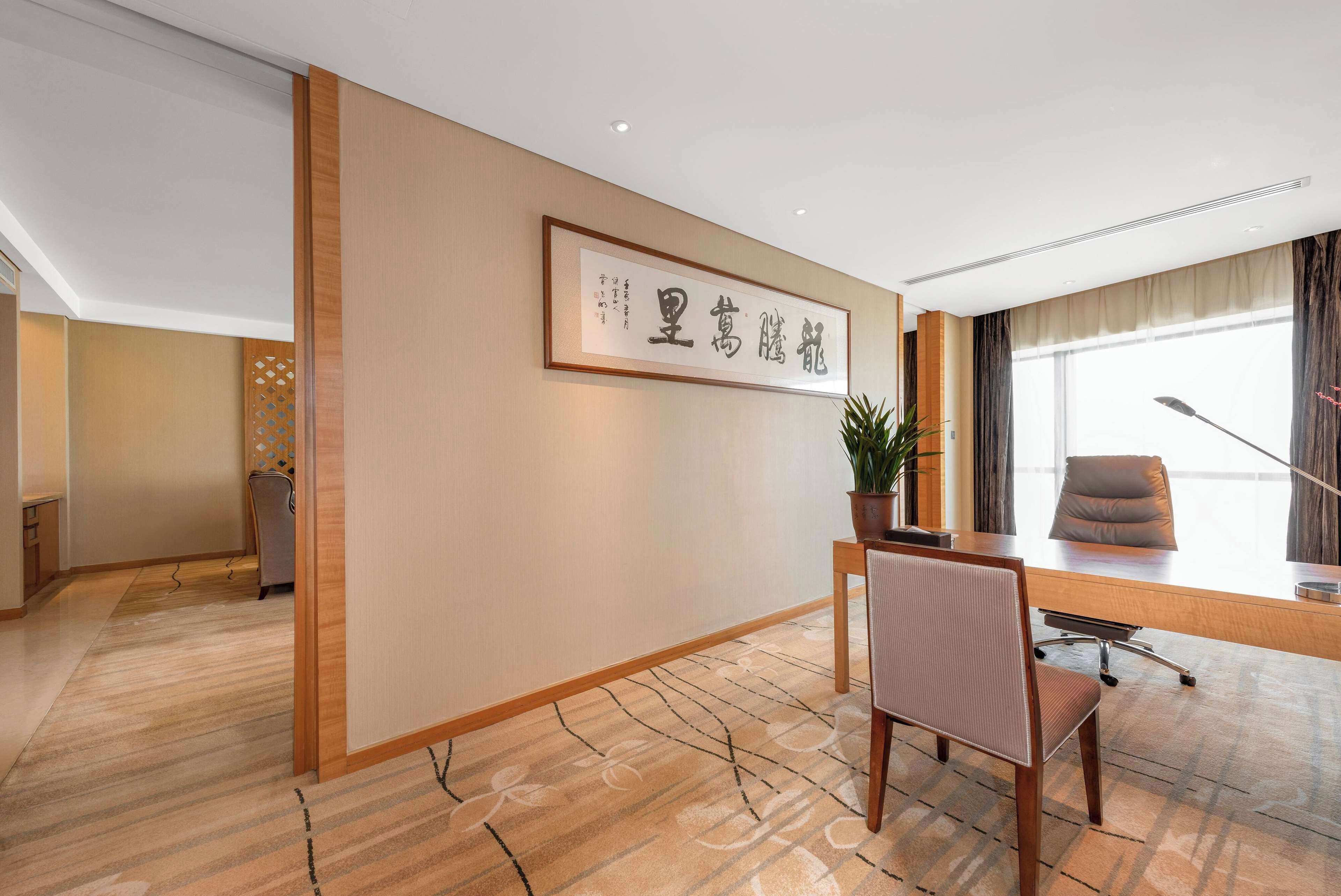 A modern office with a wooden desk, a chair, and a framed sign on the wall.