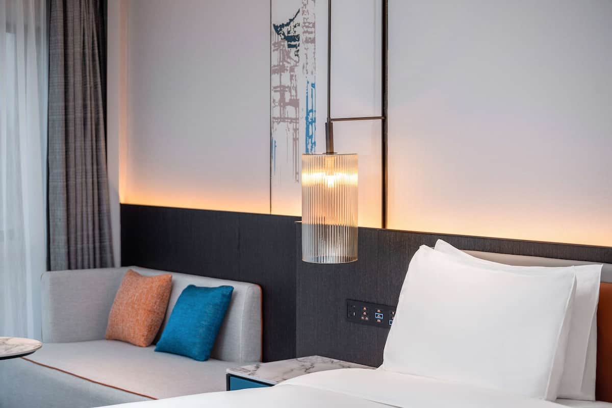 Una habitación de hotel moderna con sofá, cama y panel de control en la pared.