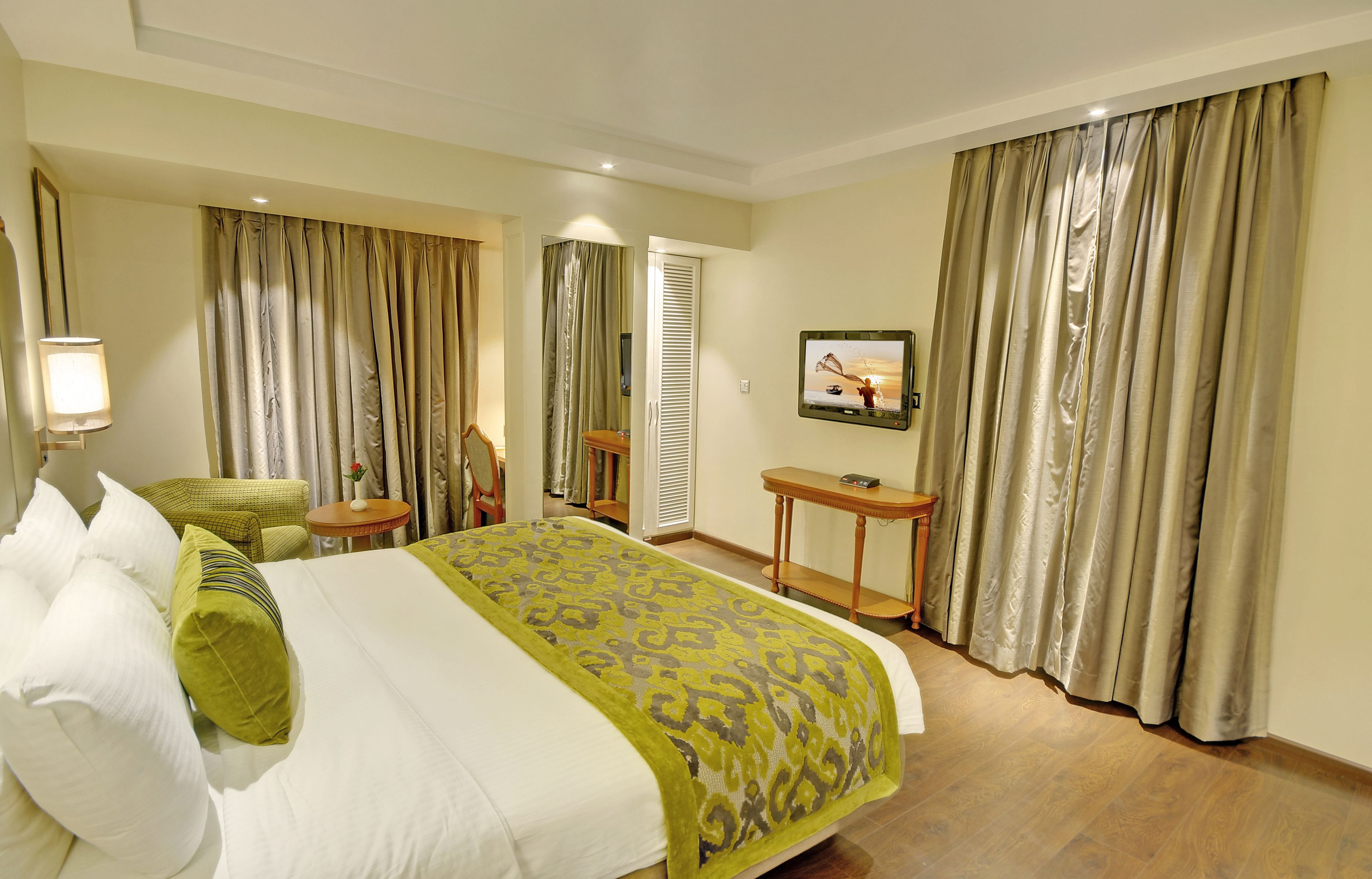 A hotel room with a bed, a desk, a chair, a TV, and curtains.