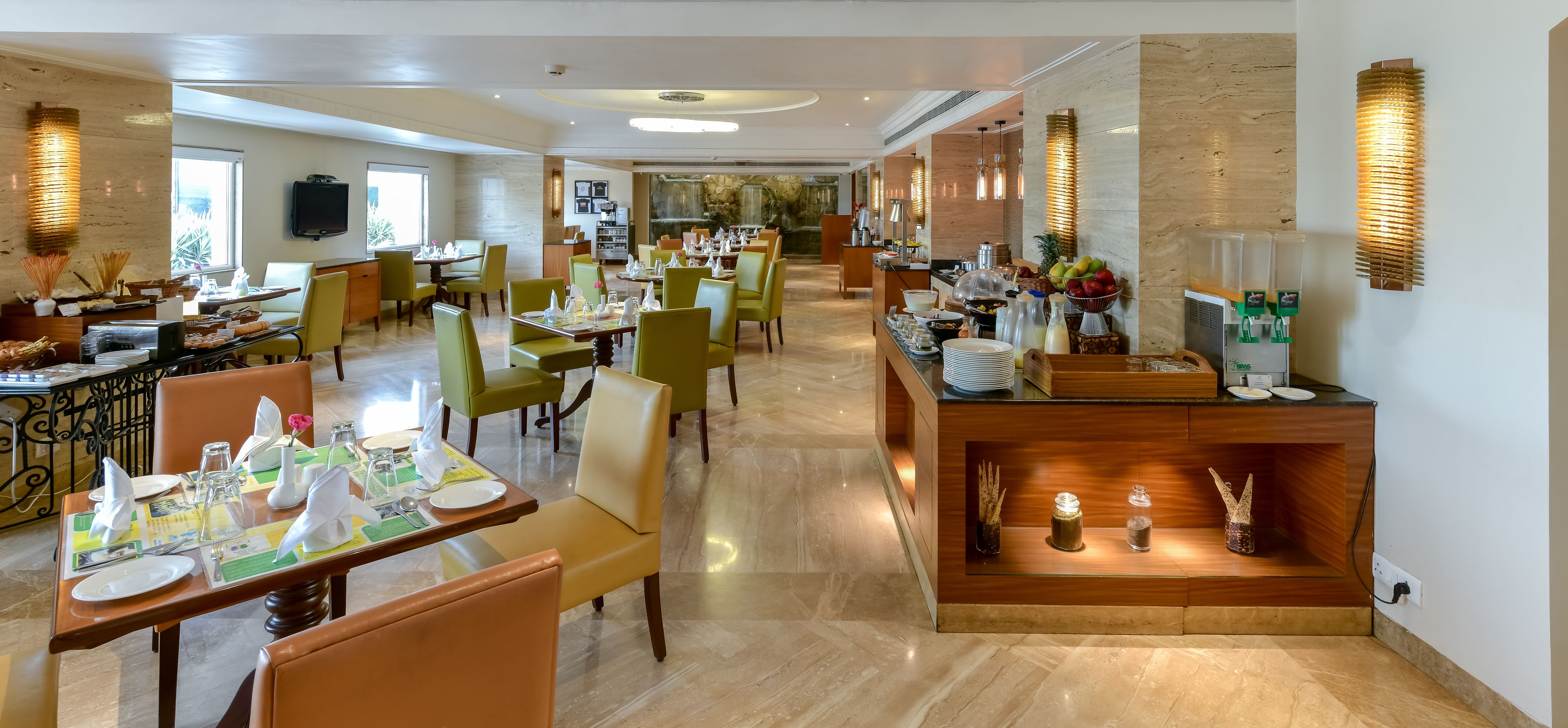 Een ruime hotel eetzaal met meerdere tafels en stoelen, een buffet en een receptiebalie.