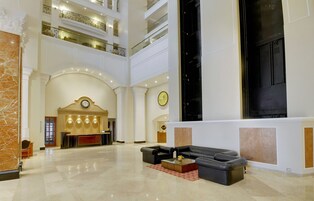 A spacious lobby with a reception desk, a black leather sofa, and a marble floor.