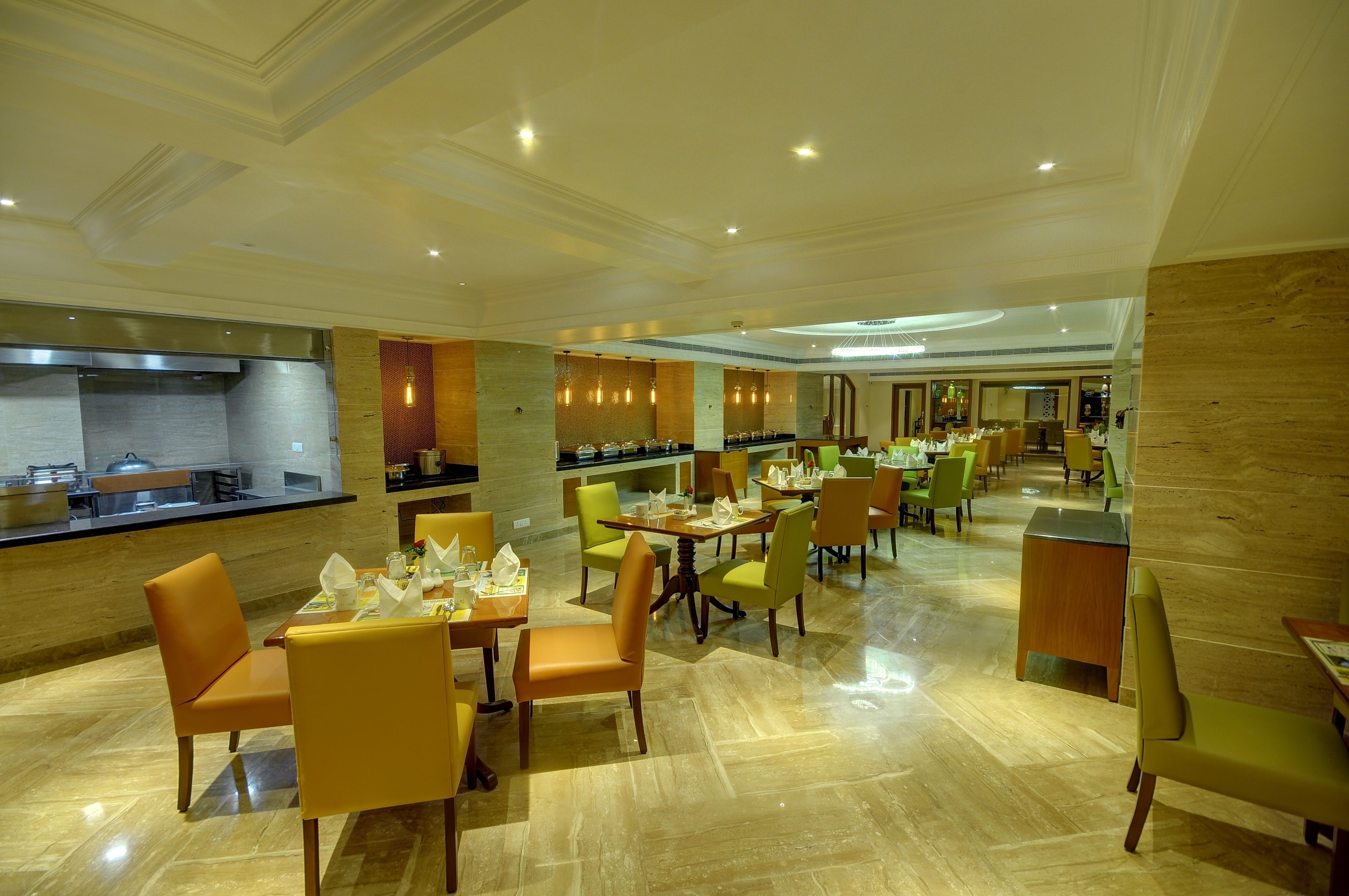 A spacious restaurant with multiple dining tables and chairs, a kitchen area, and a modern interior design.