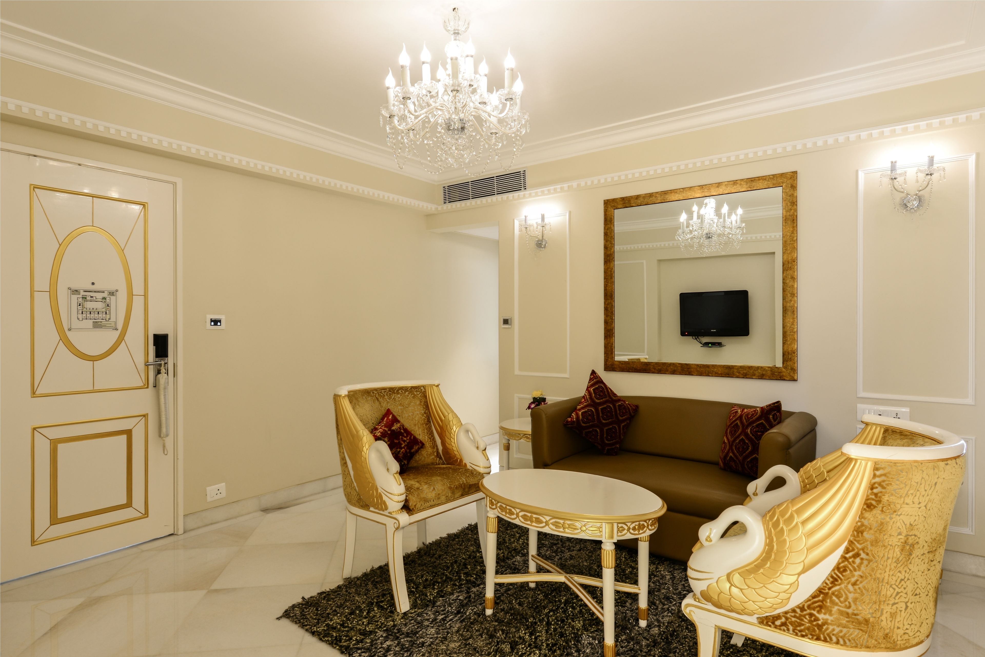 A luxurious room with a chandelier, a sofa, two armchairs, and a round table.