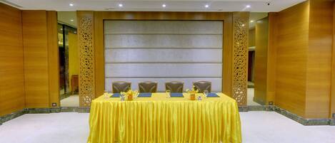 Una sala de conferencias con una mesa amarilla, sillas marrones y una alfombra estampada.