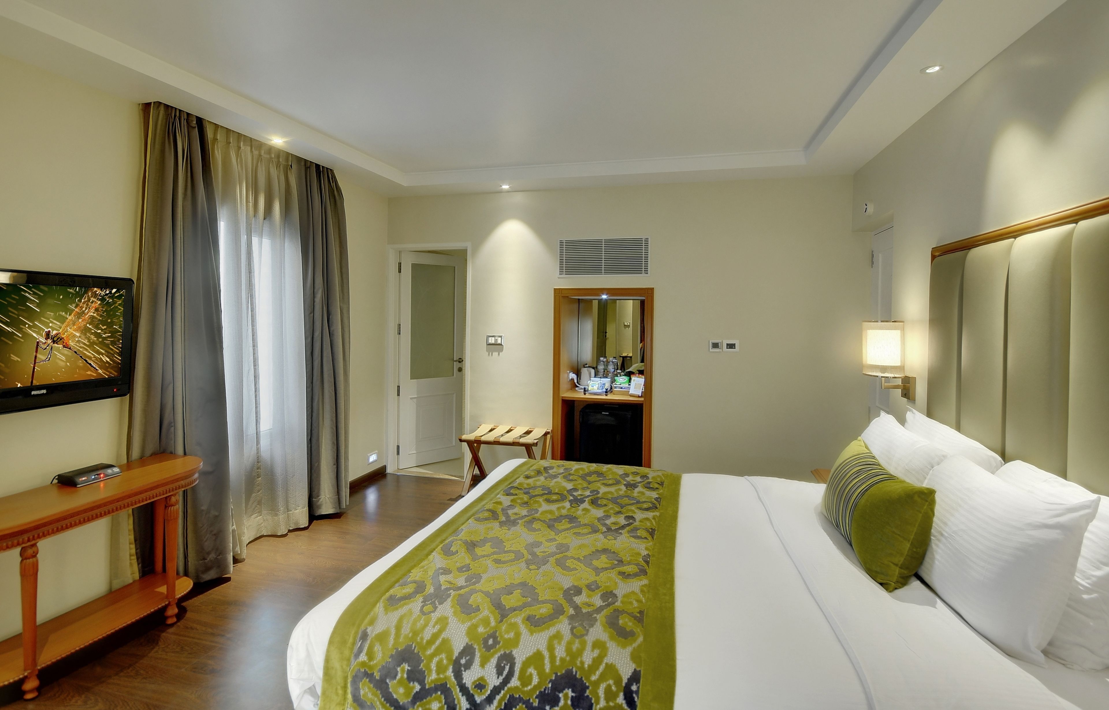 Una habitación de hotel con cama, mesita de noche, espejo, escritorio y silla.