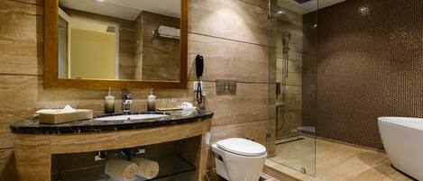 A modern bathroom with a marble sink, a large mirror, a toilet, and a glass-enclosed shower.