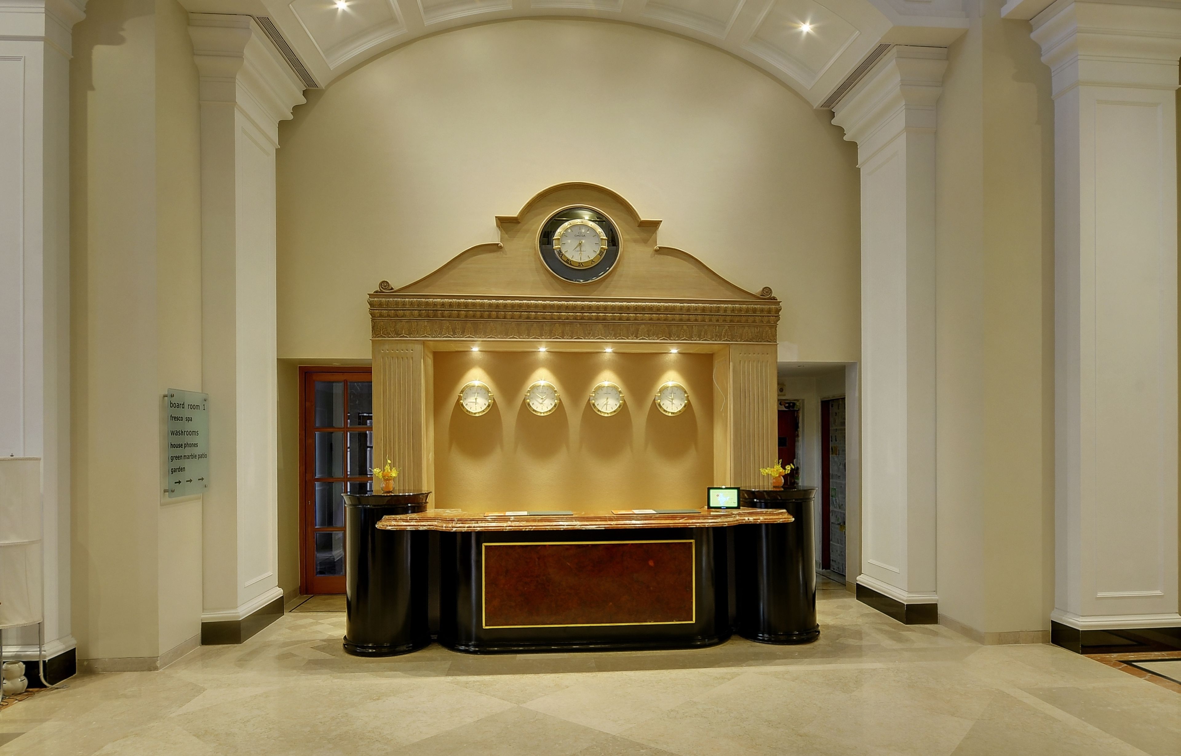 A reception area with a marble counter, a clock above it, and a sign indicating room types.