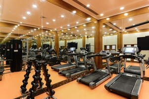 Un gimnasio con cintas de correr, máquinas de pesas y un espejo grande.