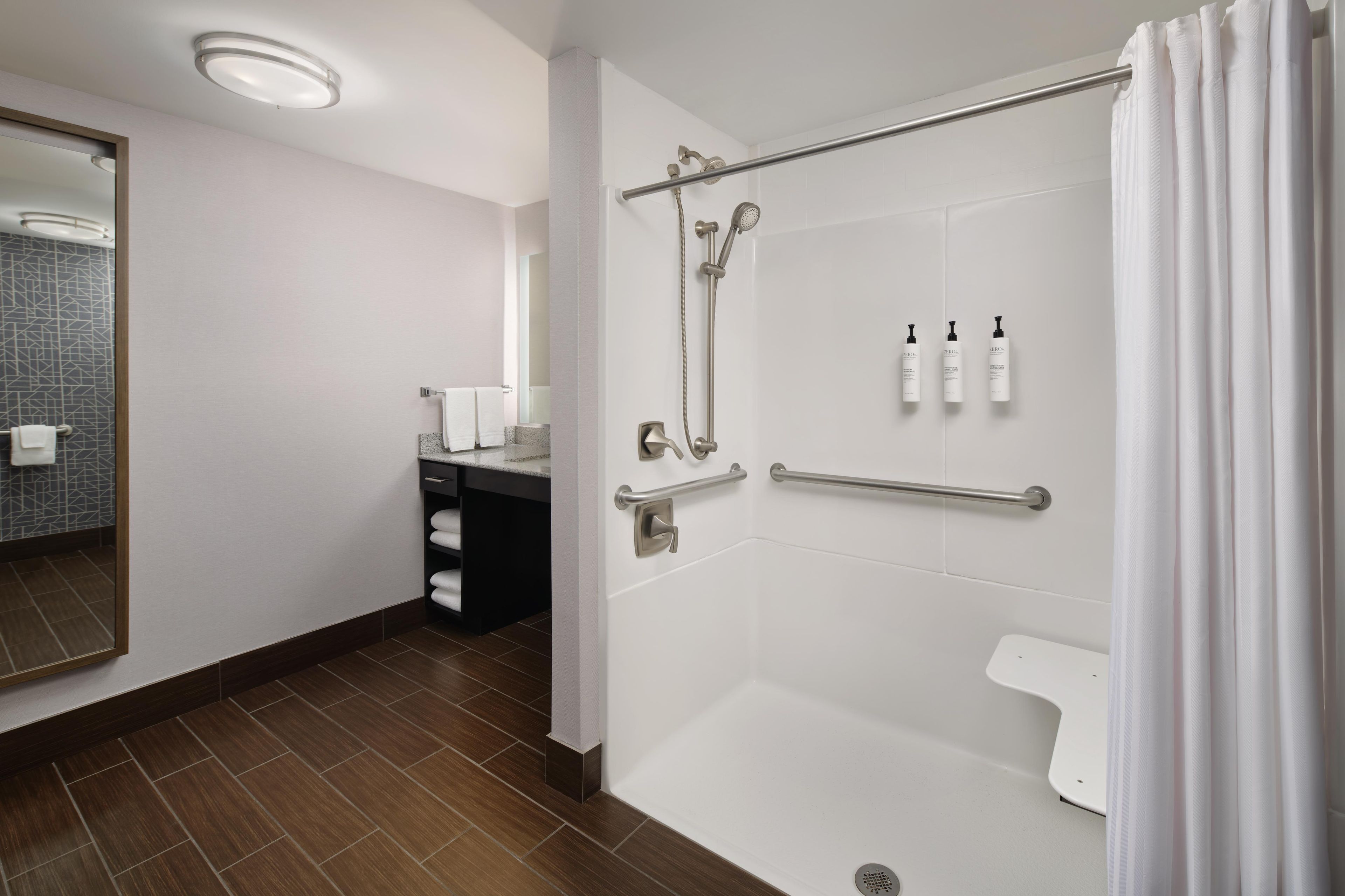 Un bany modern amb banyera, dutxa i un lavabo amb mirall.