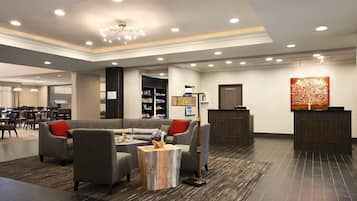 En moderne lobby med sofa, stole, sofabord, en reception og en reol.