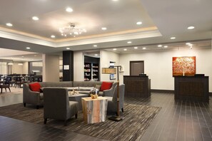 A modern lobby with a sofa, chairs, a coffee table, a reception desk, and a bookshelf. - Homewood Suites by Hilton Columbus/OSU, OH (Columbus)