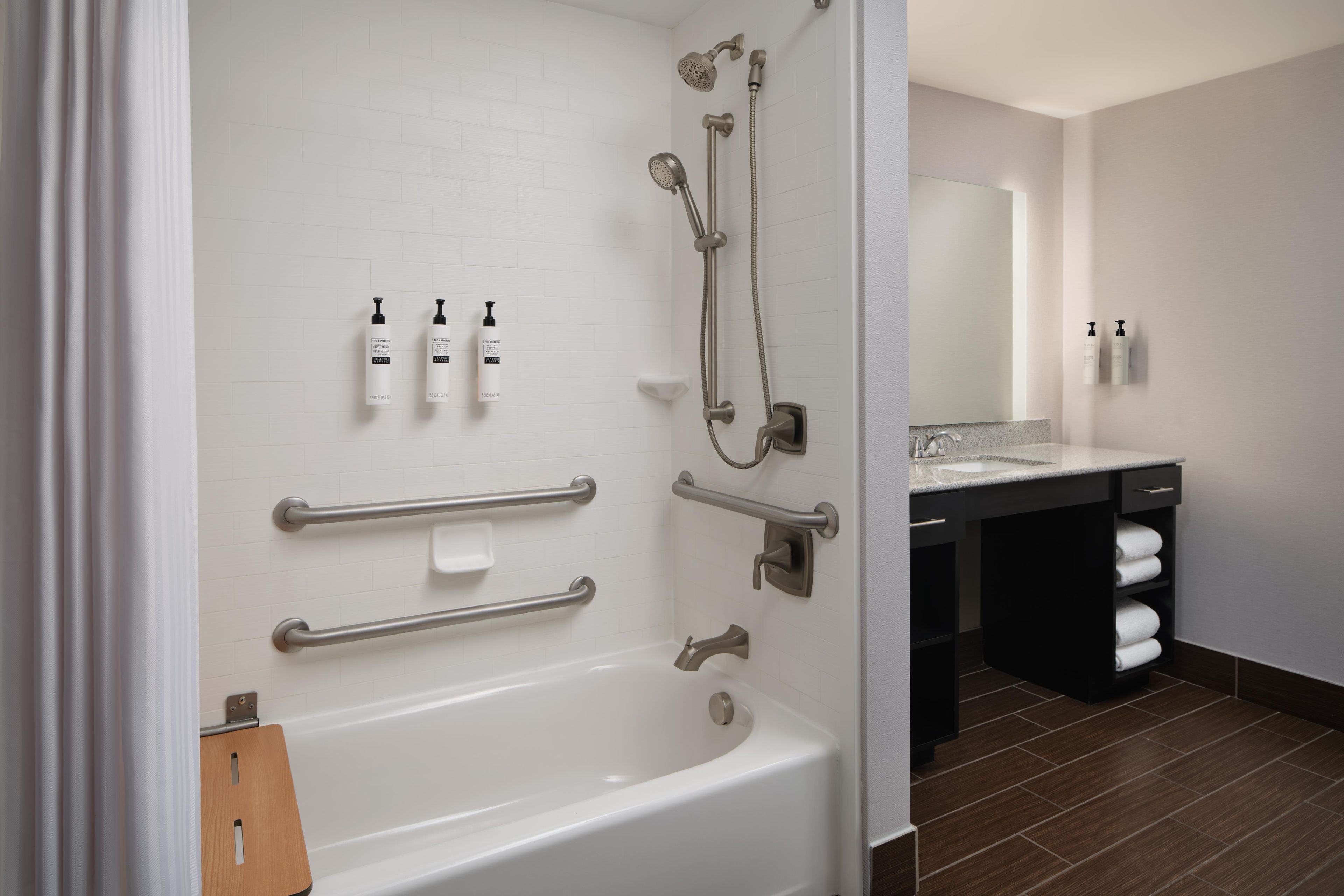 Ein modernes Badezimmer mit Badewanne, Dusche und Haltegriffen.