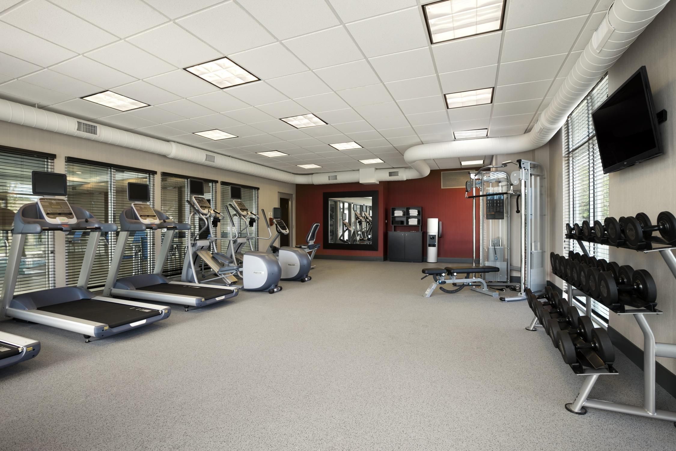 A gym with treadmills, elliptical machines, and a weight rack.