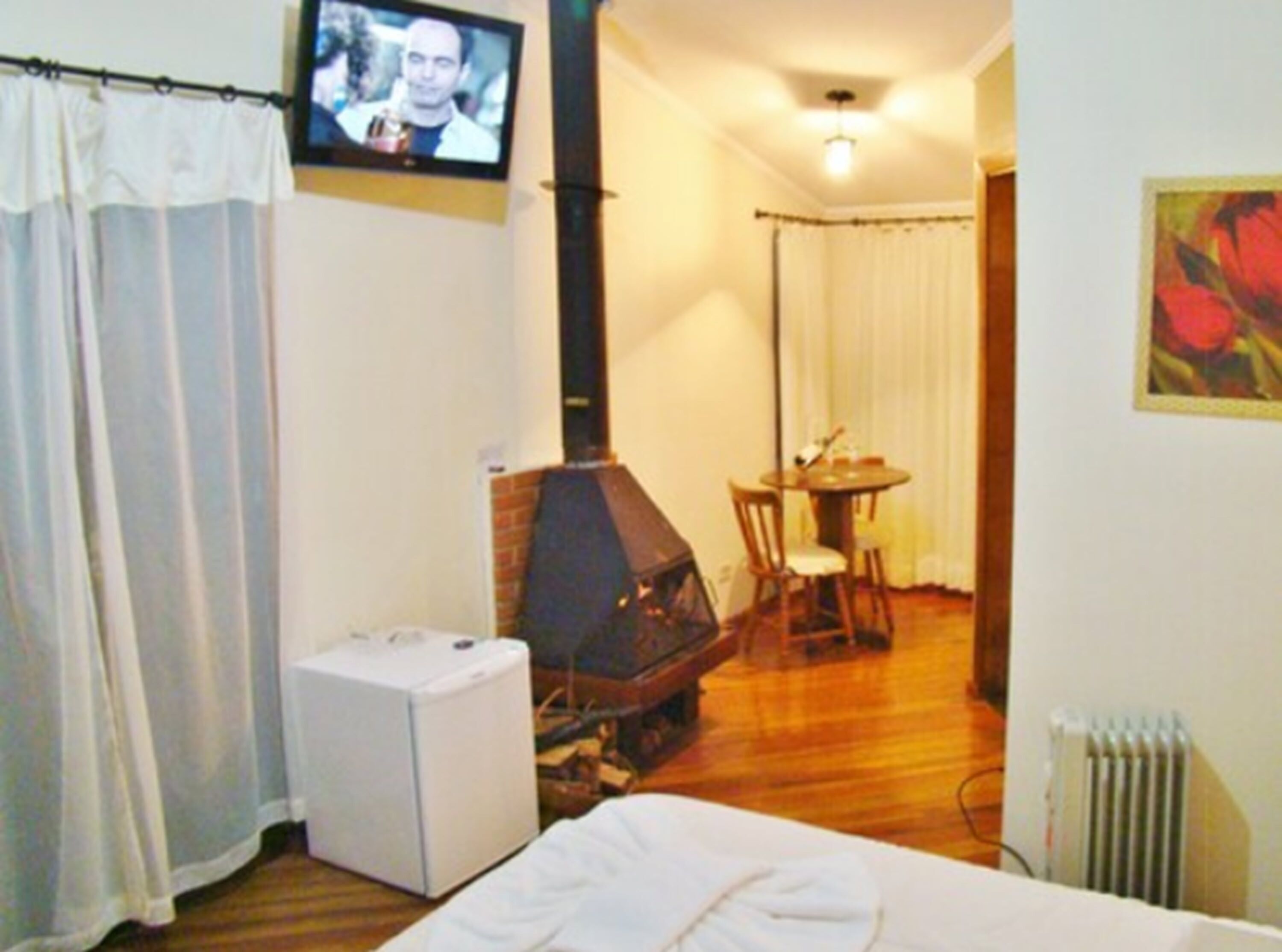 Quarto com lareira, televisão, cama e área de jantar.