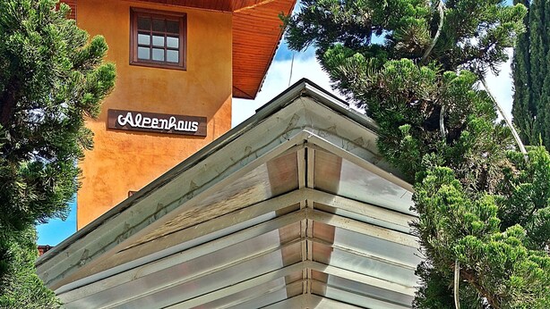 Un edificio con un letrero que dice Aleenhaus y una entrada empedrada con un banco.