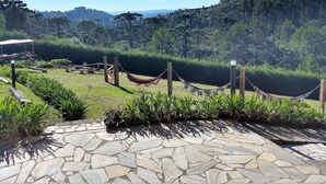 Un patio empedrado con una hamaca y vistas a un paisaje verde exuberante y montañas distantes.