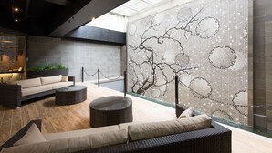 Un área de estar moderna con un sofá, mesas redondas y una pared decorativa.
