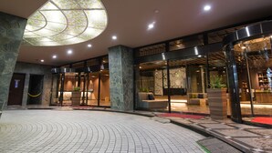 Vestíbulo de hotel con tragaluz circular, pilares de piedra, mostrador de recepción y zona de estar.